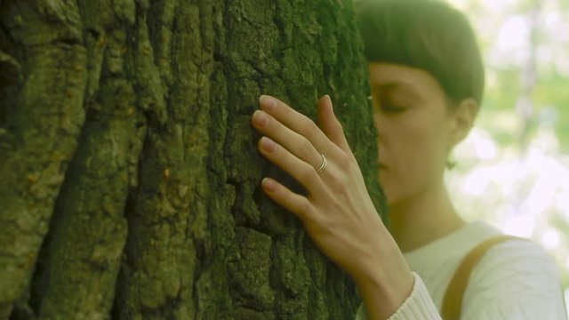 Girl hugs the big tree in the forest, love for nature. Woman touching bark, close up.