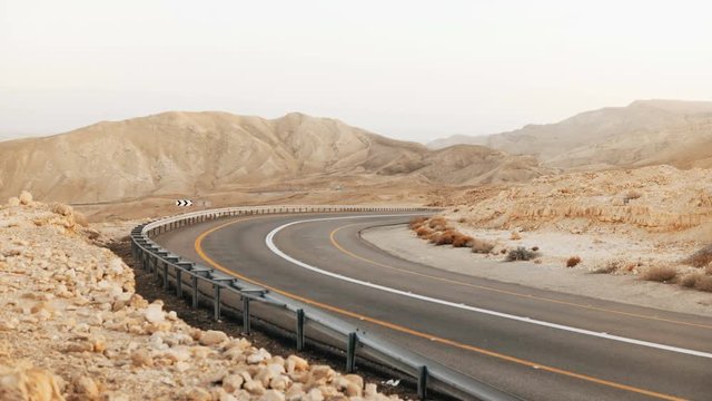 View of empty asphalt road curve in Israel desert. 4K. Roadway in ancient Negev Desert scenery. Modern transportation.