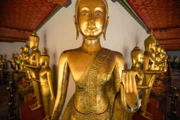 row of golden buddha statues in Wat Pho temple in Bangkok , Thailand