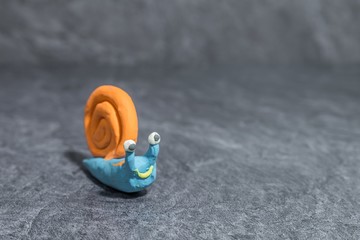 Lustige Schnecke aus Knetmasse vor grauem Hintergrund