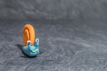 Lustige Schnecke aus Knetmasse vor grauem Hintergrund