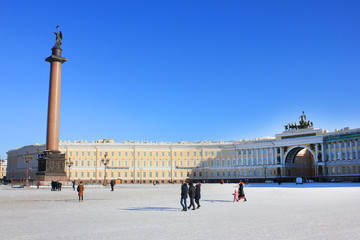Obraz premium Palace Square Winter Panorama in St. Petersburg, Russia. Alexander Column and Arch of General Staff Building Scenic Cityscape View with Tourists Walking Around. Sunny Winter Day Travel Wallpaper. 