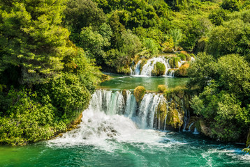Piękny wodospad wśród zielonych drzew. Krajobraz w paku Krka w Chorwacji.