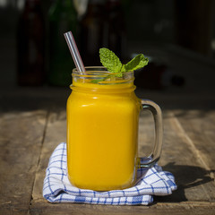 Fresh organic mango shake in glass mug on wooden table, close up
