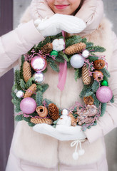 Girl outside holding decorated christmas wreath