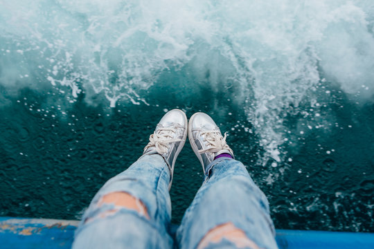 Woman's Feet In Silver Snickers Infront Of The Sea Texture.