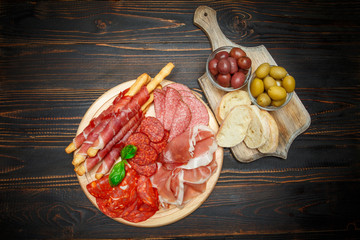 Cold smoked meat plate with pork chops, prosciutto, salami and bread sticks