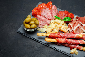 Cold smoked meat plate with pork chops, prosciutto, salami and bread sticks