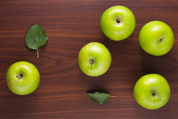 Green apples with leaves on dark wooden table Top view