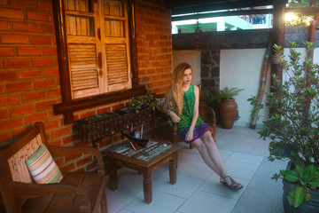 young woman sitting on armchair on terrace in summer day