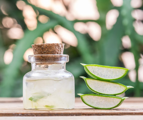Fresh aloe leaves and aloe gel in the cosmetic jar on wooden table.