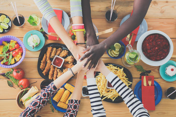Top view of group of people having dinner together while sitting at wooden table. Food on the table. People eat fast food.