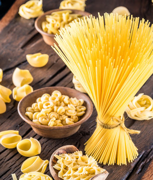 Different pasta types on wooden table.