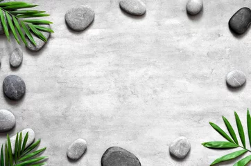 Wallpaper murals Spa Grey spa background, palm leaves and grey stones, top view