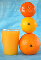 Orange, lemon, mandarin and yellow juice in a glass on blue background
