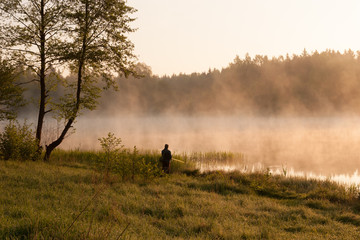 Obraz na płótnie Canvas Morning fishing. Fisherman fishing at lake. Foggy morning.