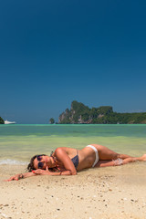 Fototapeta na wymiar Young woman in bikini laying by the tropical sea