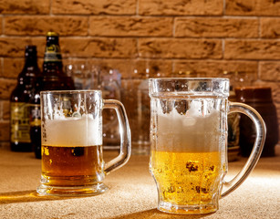 Mugs with beer on the background of glasses and brick wall.