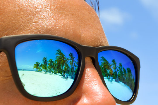 Reflection Of White Beach With Palms In The Man's Sunglasses, Man At The Beach With Sunglasses