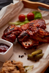 Ribs cooked on the grill with sauerkraut. On parchment paper, decorated with cucumbers and cherry tomatoes