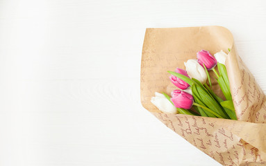 Fresh colorful tulips bouquet with ribbon over wooden background with copy space