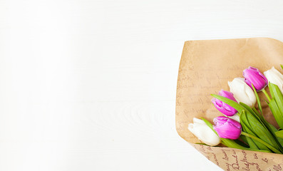 Fresh colorful tulips bouquet with ribbon over wooden background with copy space