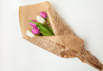 Fresh colorful tulips bouquet with ribbon over wooden background with copy space