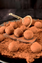 Chocolate truffles covered with cacao powder on a black plate