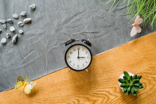 Switch to summer time on alarm clock with wooden background from above