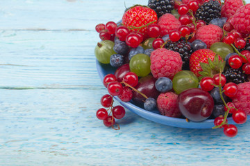 Various summer Fresh berries in a bowl on rustic wooden table. Antioxidants, detox diet, organic fruits.