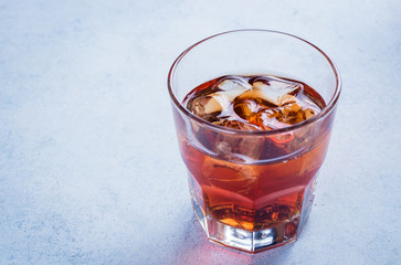 Whiskey with ice in glasses, rustic wood background, copy space