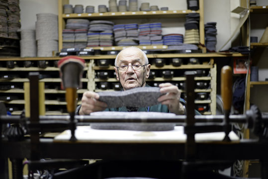 Senior shoemaker working with old-fashioned punching machine in workshop
