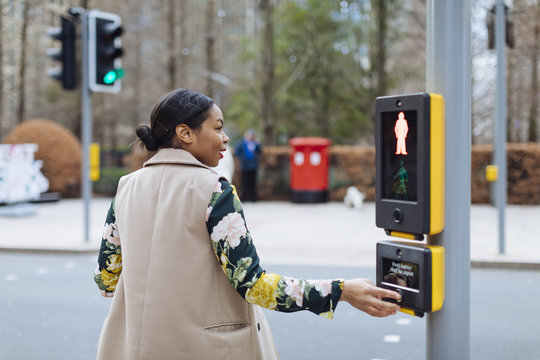 UK, London, woman pressing button of pedestrian light