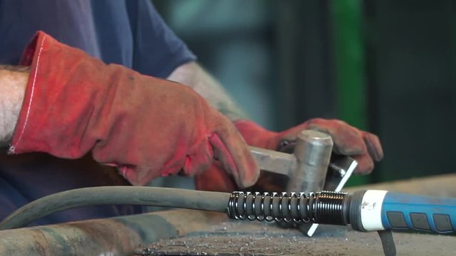 Hand Ironworker forging hot iron in workshop whith hammer. Hands of blacksmith making horseshoe