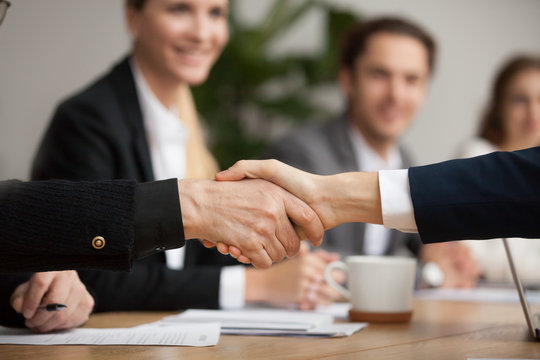 Hands of senior and young businessmen shaking at group meeting, two partners of different age handshaking making agreement or good deal, concluding contract help support concept, close up view
