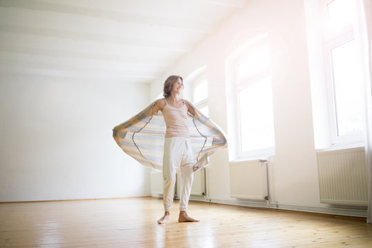 Happy mature woman standing in empty room in sunlight