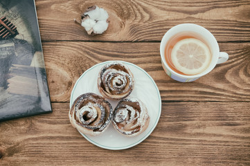 Fragrant tea with lemon and fresh homemade cookies on a table made of textured wood.