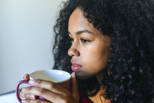 Portrait Of Pensive Young Woman With Cup Of Milk