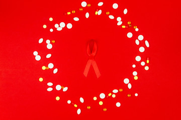 Red tape as symbol of AIDS / HIV illness with medicine drugs isolated on red background