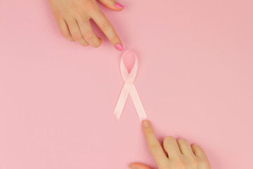 Women's hands with pink tape as symbol of women illness mammary cancer isolated on pink background