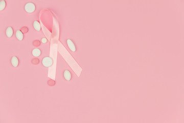 Pink tape as symbol of women's illness mammary cancer lying with medical drugs on pink background