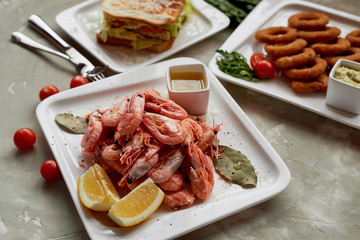 Beer snack in the pub or bar. Shrimp, mouth-watering sandwich and Golden onion rings.