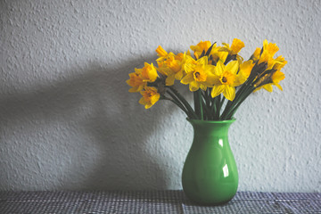 A bunch of yellow daffodils in a green vase