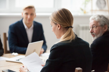 Serious businesswoman reading document contract at team meeting, female employee or manager holding...
