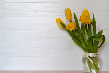 Yellow tulips in vase on the table. Spring background.