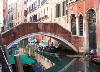 a small bridge in a canal in Venice with the moored boats of the residents. Italy