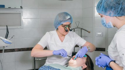 Woman at dentist clinic gets dental treatment to fill a cavity in a tooth. Dental restoration and...