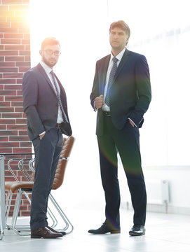 Two businessmen are standing in a modern office