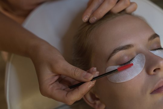 Beautician giving eyelash extension treatment to female customer