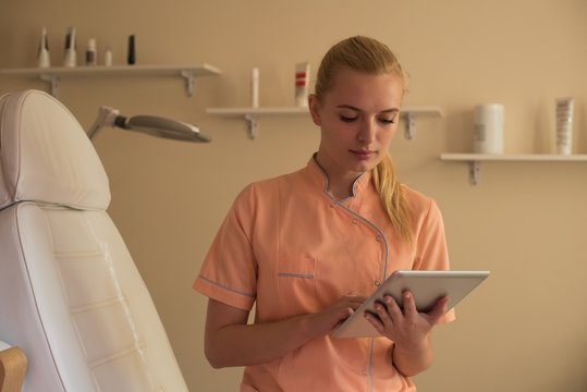 Female beautician using digital tablet in parlour